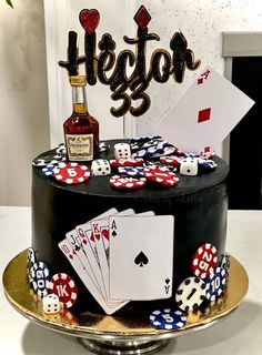 a birthday cake decorated with playing cards, dice and a bottle of liquor on top