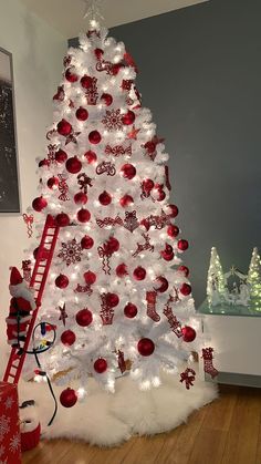 a white christmas tree decorated with red and silver ornaments