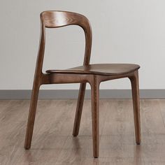 a wooden chair sitting on top of a hard wood floor next to a white wall