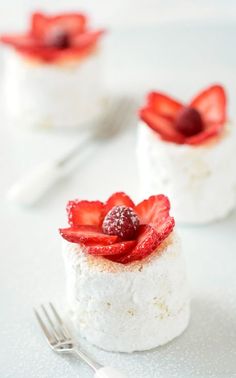 three small desserts with strawberries and cream on them