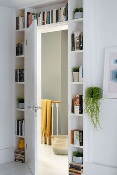 an open door leading into a room with bookshelves and plants on the shelves