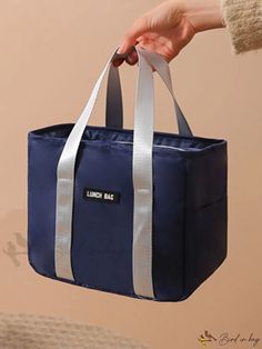 a person holding a blue lunch bag with white trimmings on the handles and sides