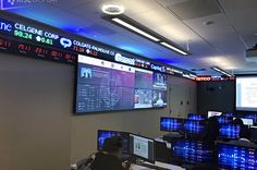 a man sitting at a desk in front of multiple computer monitors with screens on the wall