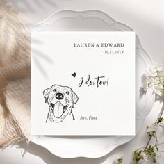 a white plate with a drawing of a dog on it next to flowers and a napkin