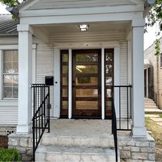 the front door of a white house with black railings