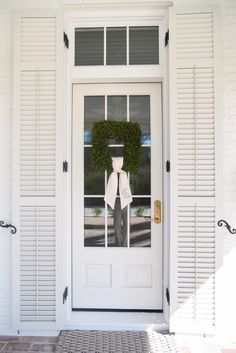 a white door with shutters and a wreath on it