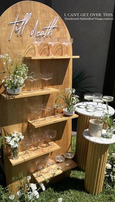 a wooden shelf with wine glasses and flowers on it in front of a sign that says hello north