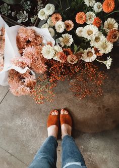 a person standing in front of a bunch of flowers with their feet on the ground