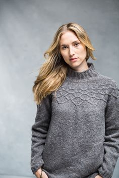 a woman with long hair wearing a gray sweater