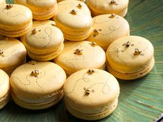 a plate filled with lots of yellow macaroons covered in honeybees and sitting on top of each other