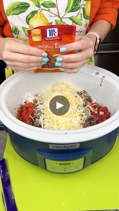 a woman holding up a box of frozen food in her hands while standing next to a slow cooker