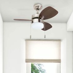 a ceiling fan mounted to the side of a window in a room with white walls