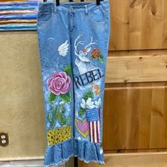 a pair of jeans hanging on a clothes rack with the word rebel painted on it