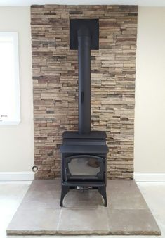 a black stove sitting inside of a room next to a stone wall with a window