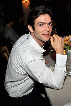 a man sitting at a table with flowers in front of him and looking to the side