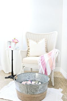 a white chair sitting next to a metal bucket on top of a carpeted floor