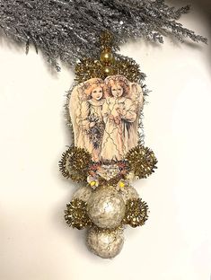 an ornament hanging from the side of a christmas tree with angels on it