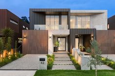 a modern house is lit up at night with lights on the front and side windows