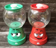 two colorful gumball machines sitting on top of a wooden table next to each other