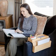 a woman sitting on a couch with a book and pen in her hand while looking at something