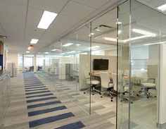 an office with glass walls and carpeted flooring is seen in this image from the inside