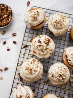 there are many donuts with icing and pecans on the cooling rack next to it