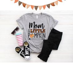 Mom of the little Pumpkin birthday shirt! We love this orange plaid print paired with the super cute patch print pumpkin - so cute for a fall theme birthday! We do have a matching one for Dad and the Birthday child in our shop. Every tee is handmade to order with love. Printed on our Unisex Adult Tees, these do run large. For a women's fit, we do suggest sizing down. For a looser fit, size as you would normally purchase. Please note since all tees are handmade, graphic placement may vary slightl Playful Tops With Letter Print For Fall, Playful Letter Print Tops For Fall, Casual Tops For Fall Birthday, Graphic Print Tops For Birthday In Fall, Cute Name Print Tops For Fall, Cute Tops With Name Print For Fall, Fun Cotton Shirt For Mother's Day, Cute Orange Cotton Shirt, Cute Fall Birthday Tops