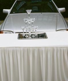 a silver car parked in front of a white table cloth with wine glasses on it