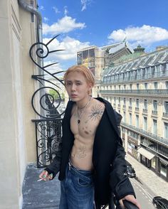 a shirtless man standing on top of a balcony next to a building with lots of windows