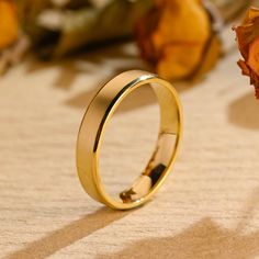 a gold wedding ring sitting on top of a table next to dried flowers and leaves