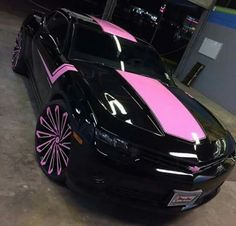 a black car with pink stripes parked in a garage