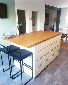 a kitchen island with two stools next to it and a television mounted on the wall