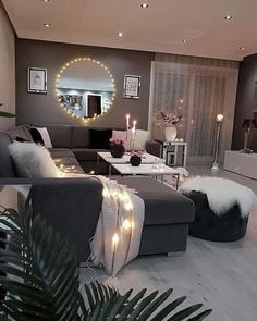 a living room filled with lots of furniture next to a mirror and lights on the wall