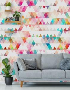 a couch sitting in front of a wall with colorful triangles painted on the wall behind it