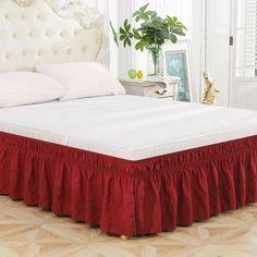 a white bed with red ruffled bedskirt