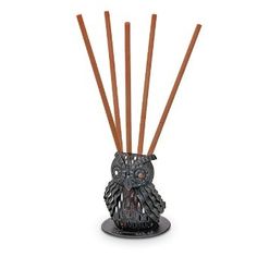 an owl shaped candle holder with reeds in it