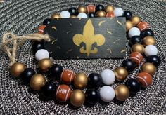 the new orleans saints bracelets are made out of wood and glass beads with gold fleur - de - lice charms