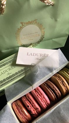 a box filled with different colored macaroons next to money