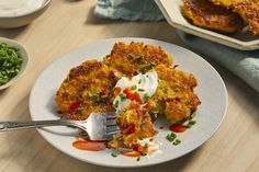 a white plate topped with crab cakes next to bowls of green beans and sauces