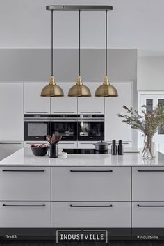 an image of a kitchen setting with white cabinets and gold pendant lights over the island