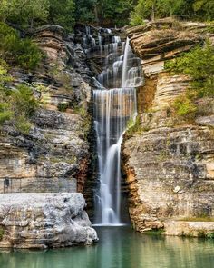 a waterfall is seen in the middle of a body of water