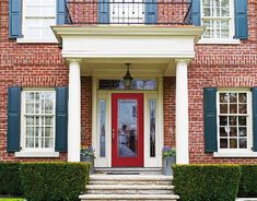 a red front door with blue shutters and white trim on a brick house in the suburbs