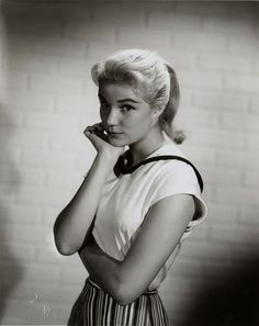 an old black and white photo of a woman with her hand on her chin looking at the camera