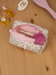 a pink and white flower sitting on top of a wooden table next to a brush