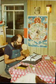 a man sitting at a table with a typewriter in his hand and looking at the screen