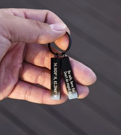 a person holding two key chains in their left hand and the other one has an inscription on it