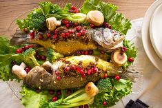 two fish on a platter with broccoli, mushrooms and pomegranates