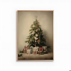 a christmas tree with presents under it in front of a white wall and framed photograph