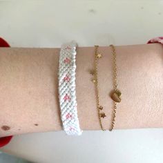 a woman's arm with two bracelets on it and one has a heart