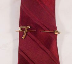 Great Hickok tie clip or tie bar.  The gold tone tie clip has a script "T" at one end and an arrow at the other.  Your tie would slip between the two ends and then the clip on the back clips to your shirt underneath your tie.  Great gift for a gentleman whose name starts with "T".  Made in U.S.A. Vintage 1970's circa Hallmarks - Signed HICKOK U.S.A. on back. Measurements - 3 1/4" long by about 1" tall. Condition - Very good. Comes in a small box, perfect for gift giving. Please review all photos and use the zoom feature.  The item photographed is the exact one you will receive.  Due to lighting effects, monitor's brightness, contrast and other settings, there might be some slight differences in the color tone/shade of the photo and the actual item.  Please consider that vintage and estate Shirt Clips, Vintage Native American Jewelry, A Script, A Gentleman, Tie Clips, Tie Pin, Tie Tack, Tie Bar, Tie Accessories